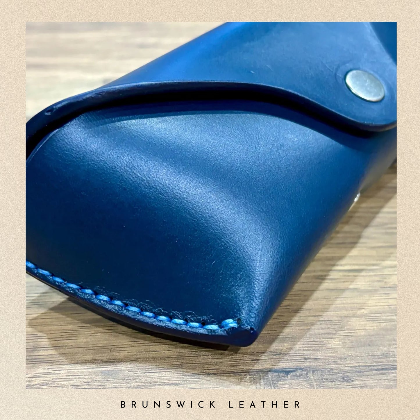 Blue leather product on a wooden surface with 'Brunswick Leather' branding.