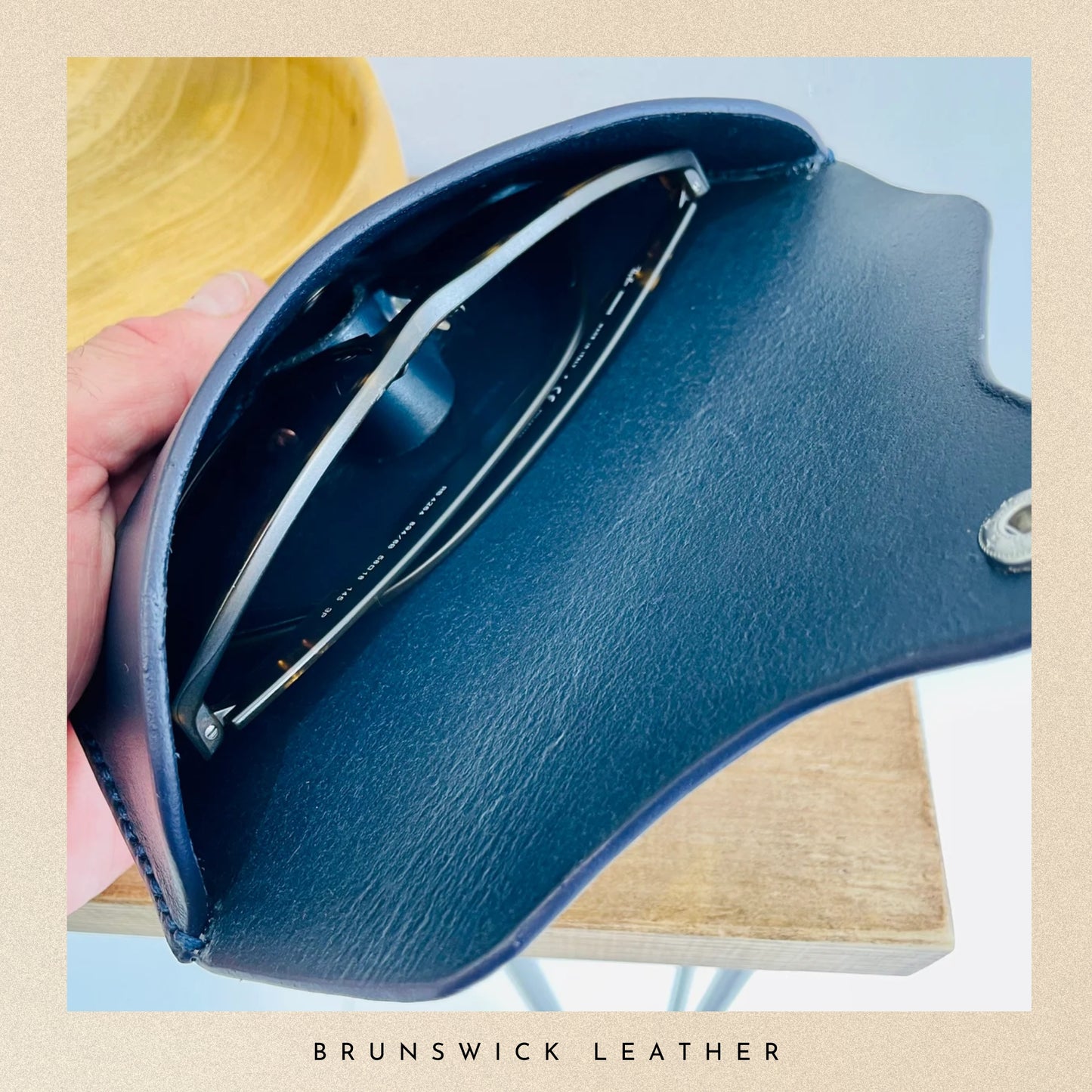 Blue leather saddle pad held by a hand with 'Brunswick Leather' branding.