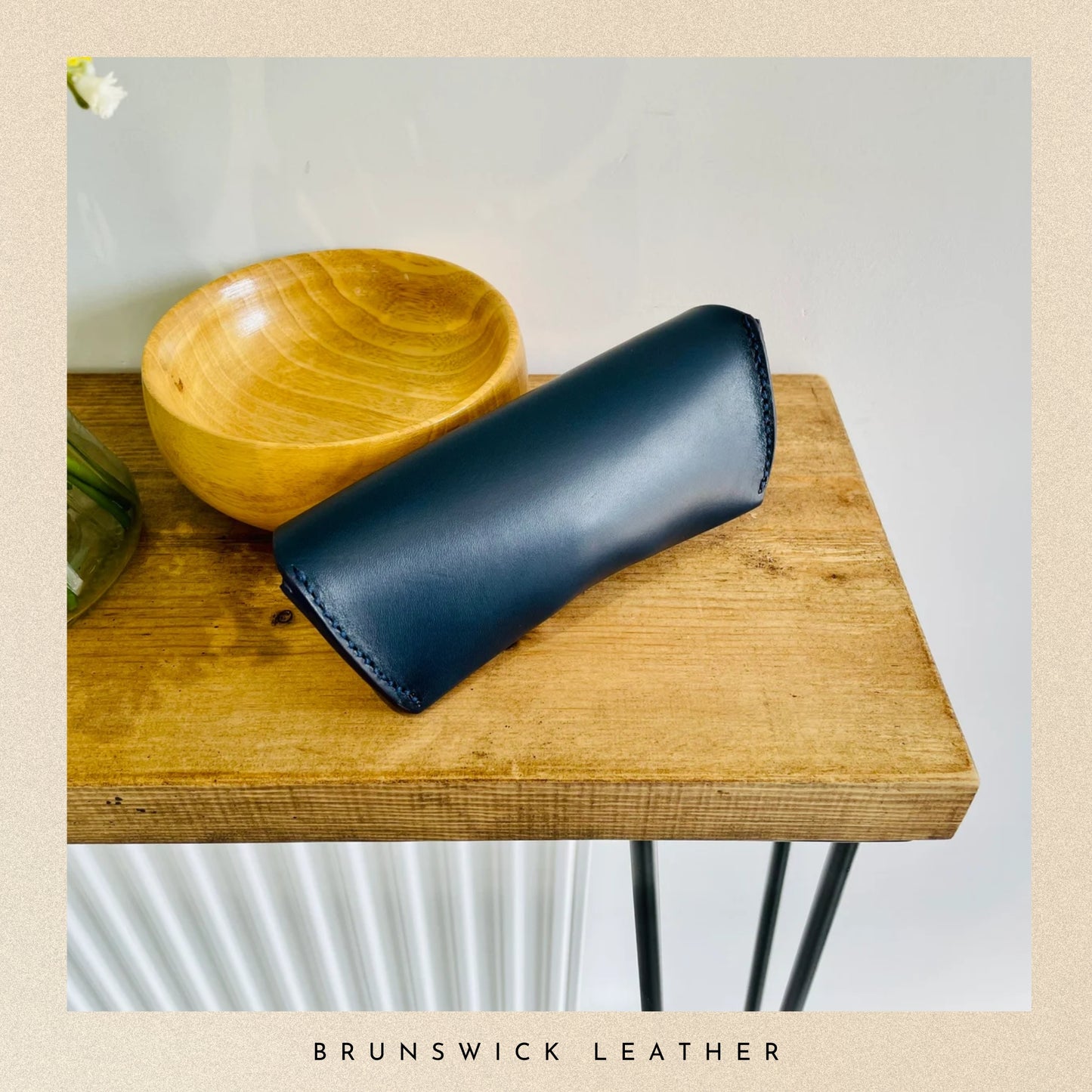 Blue leather case on a wooden surface with 'Brunswick Leather' branding.