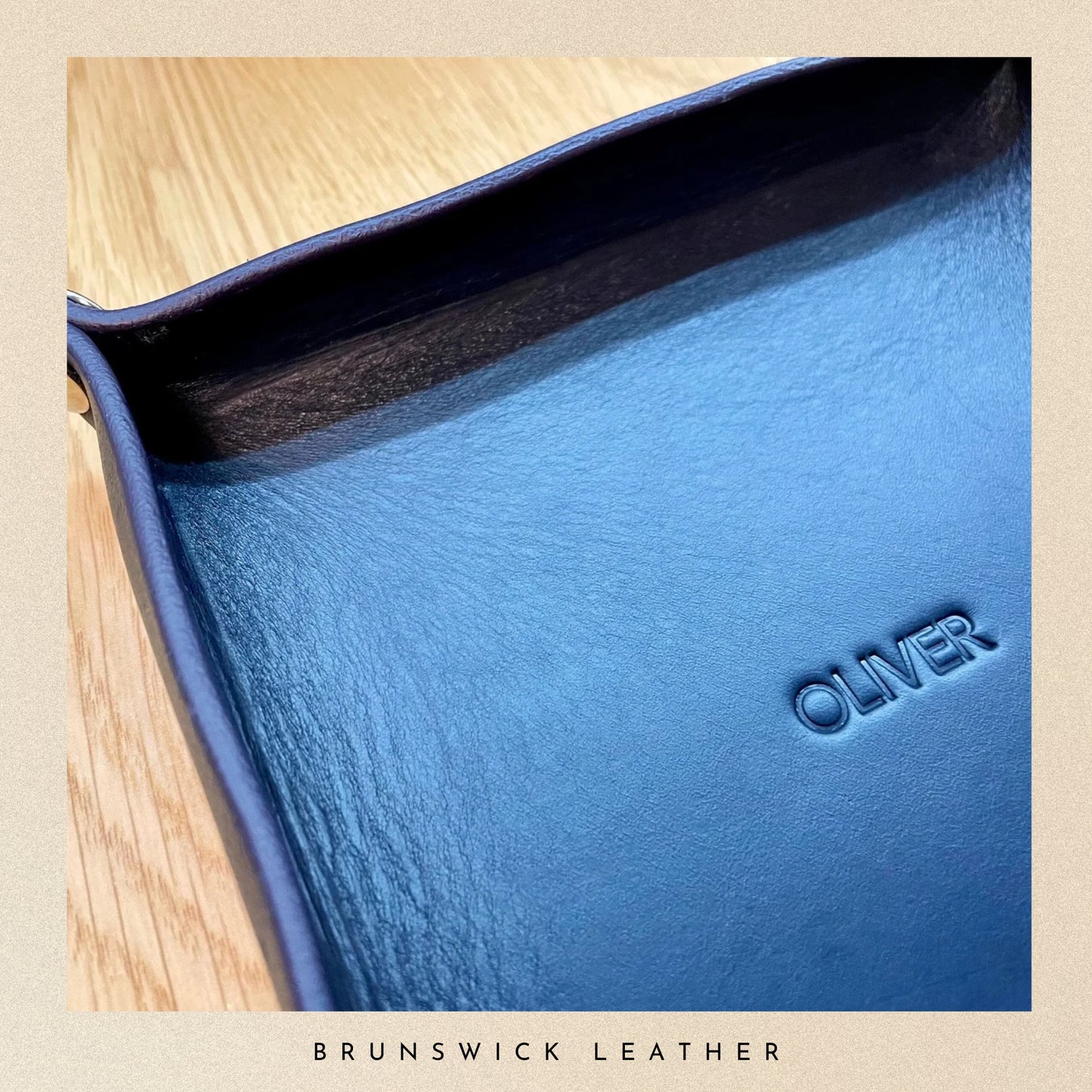 Blue leather product with 'OLIVER' branding on a wooden surface, featuring Brunswick Leather.