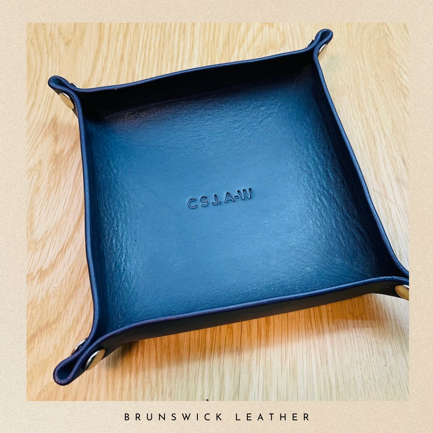 Blue leather tray with 'G.S.LAW' branding on a wooden surface, featuring Brunswick Leather.