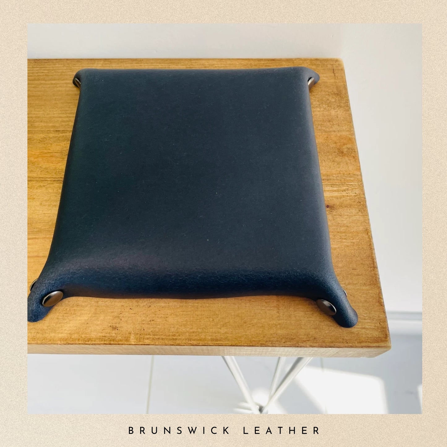 Blue leather cushion on a wooden stool with 'Brunswick Leather' branding.