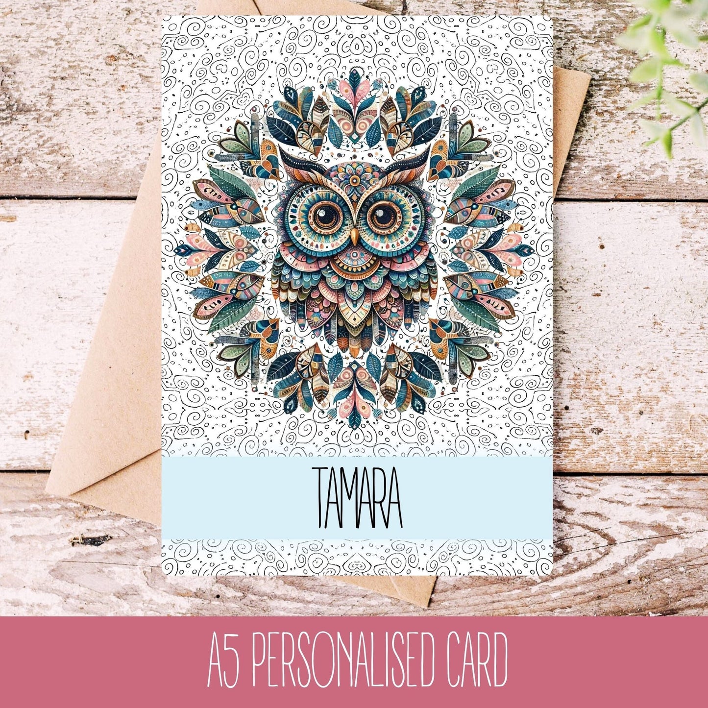 A personalised greeting card with a mandala owl design, featuring the name 'TAMARA' on the front, placed on a wooden background with a white envelope.