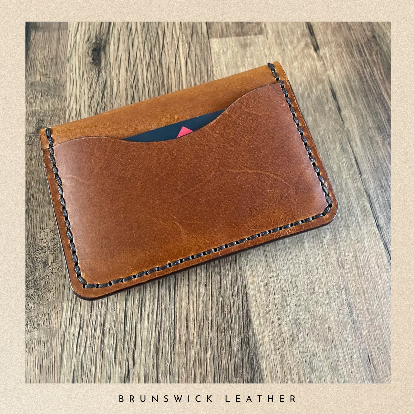 Brown leather wallet on a wooden surface with 'Brunswick Leather' branding.