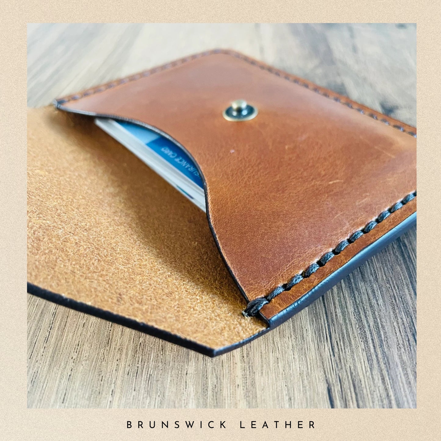 Brown leather wallet with visible stitching on a wooden surface, branded 'Brunswick Leather'.