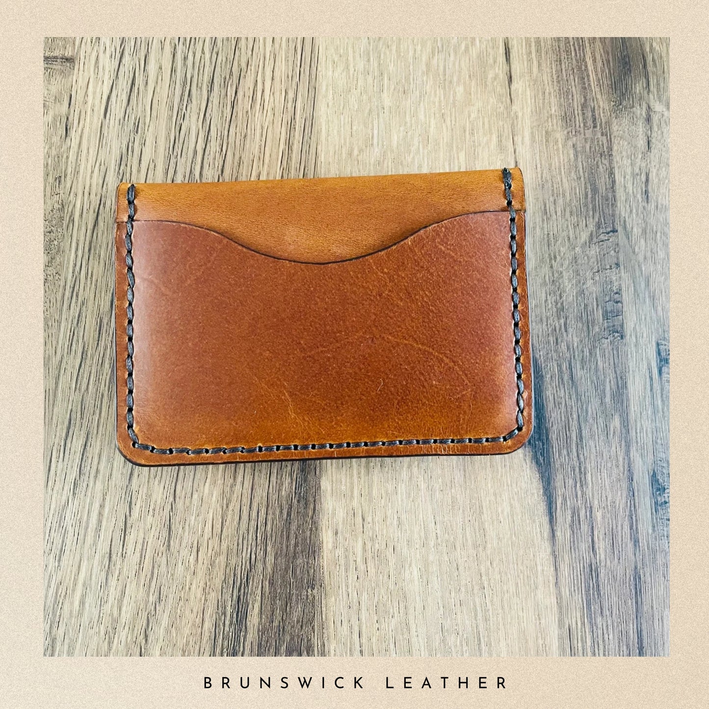 Brown leather wallet on a wooden surface with 'Brunswick Leather' branding.