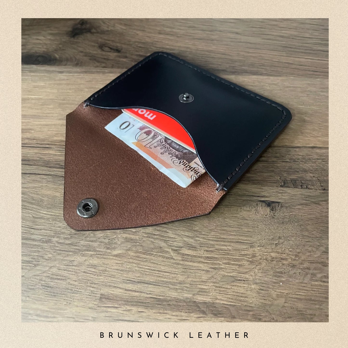 Brown leather wallet with a card on a wooden surface, branded 'Brunswick Leather'.