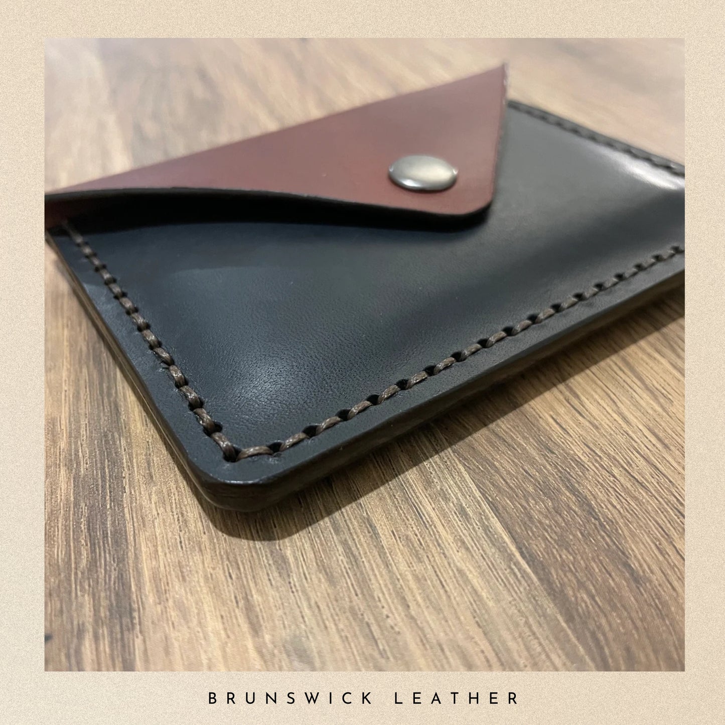 Leather wallet with brown flap on a wooden surface, branded 'Brunswick Leather'.