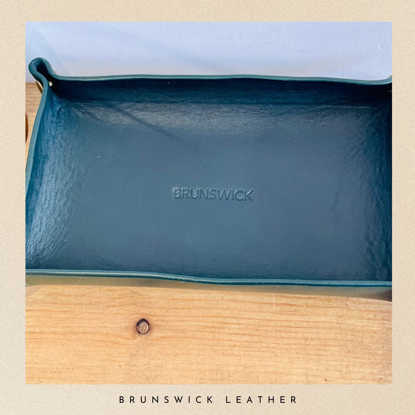 Blue leather pouch with 'Brunswick' branding on a wooden surface