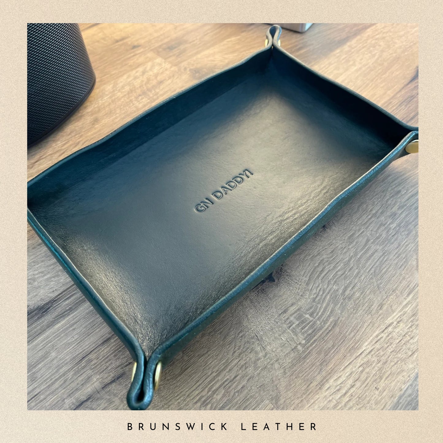 Dark green leather tray with 'For Daddy' engraving on a wooden surface, branded 'Brunswick Leather'.