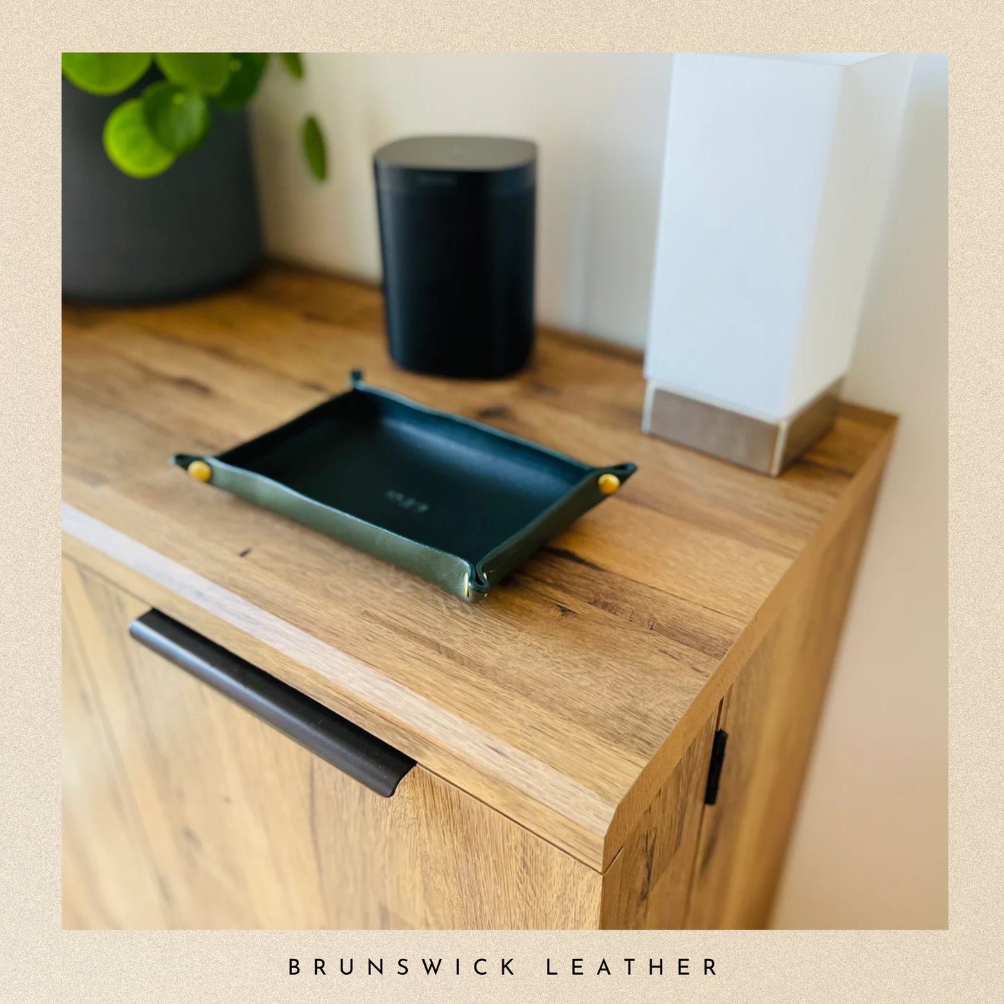 Green leather tray on a wooden surface with 'Brunswick Leather' branding.