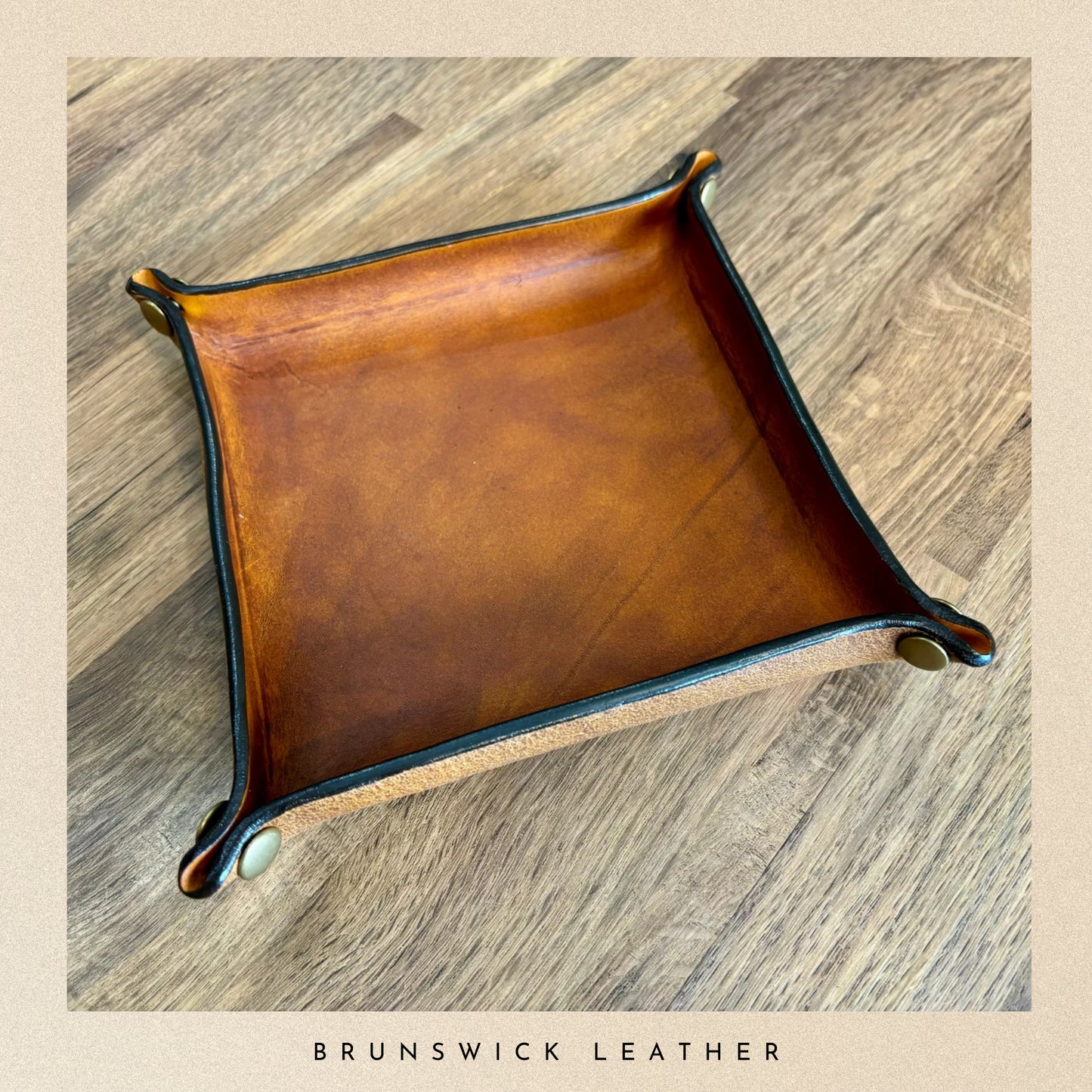 Brown leather tray on a wooden surface with 'Brunswick Leather' branding.