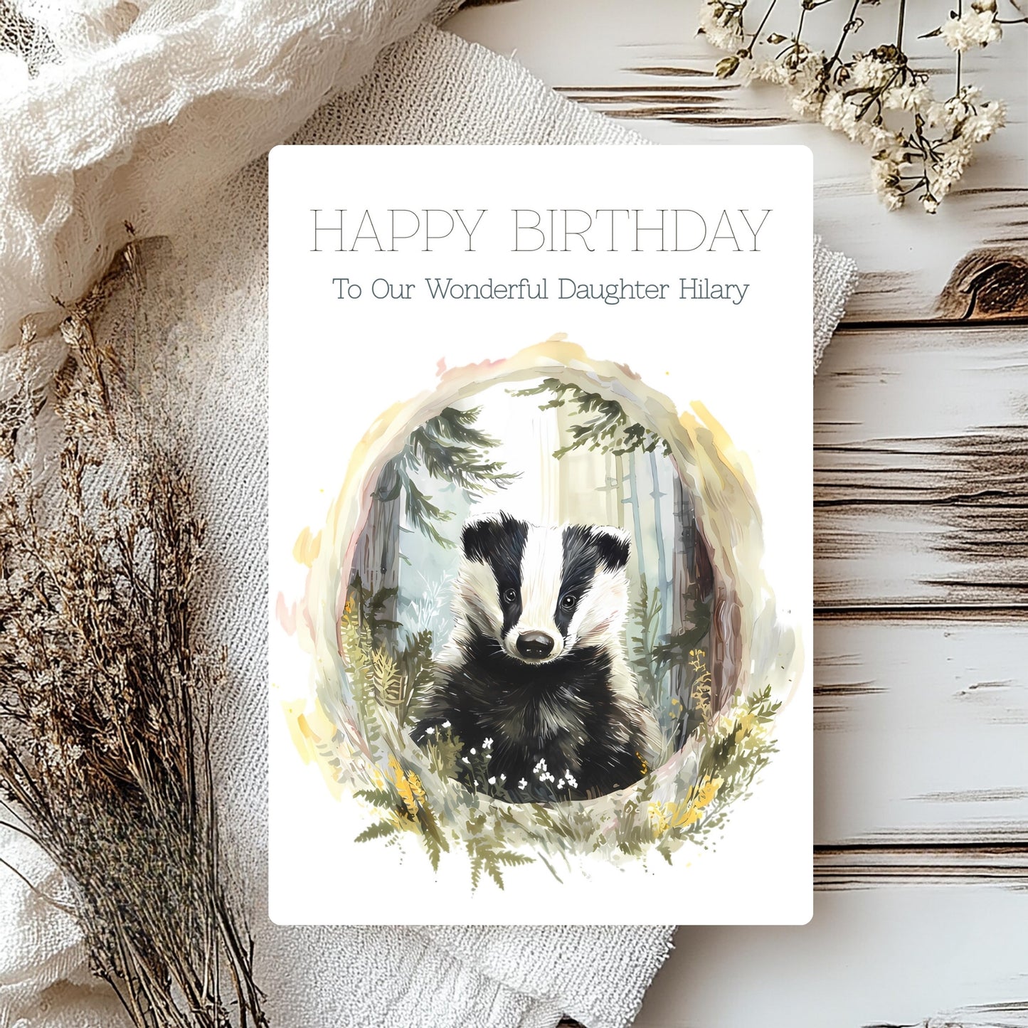 Birthday card with a badger illustration on a wooden surface with flowers.