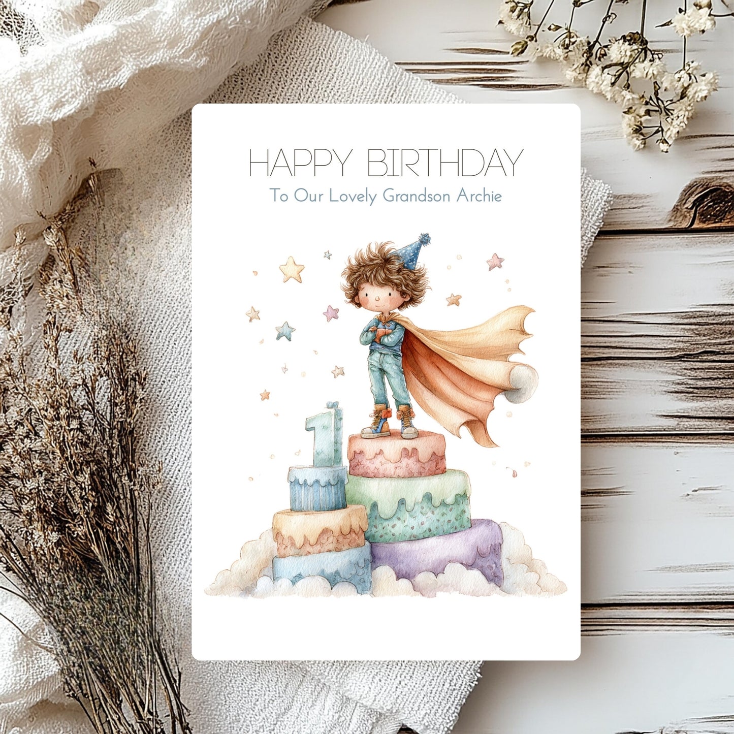 Personalised grandson card with a number 1 and little boy in a cape on top of cake.