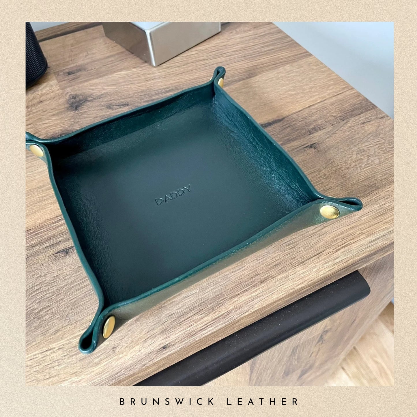 Green leather tray with 'Daddy' engraving on a wooden surface, branded 'Brunswick Leather'.