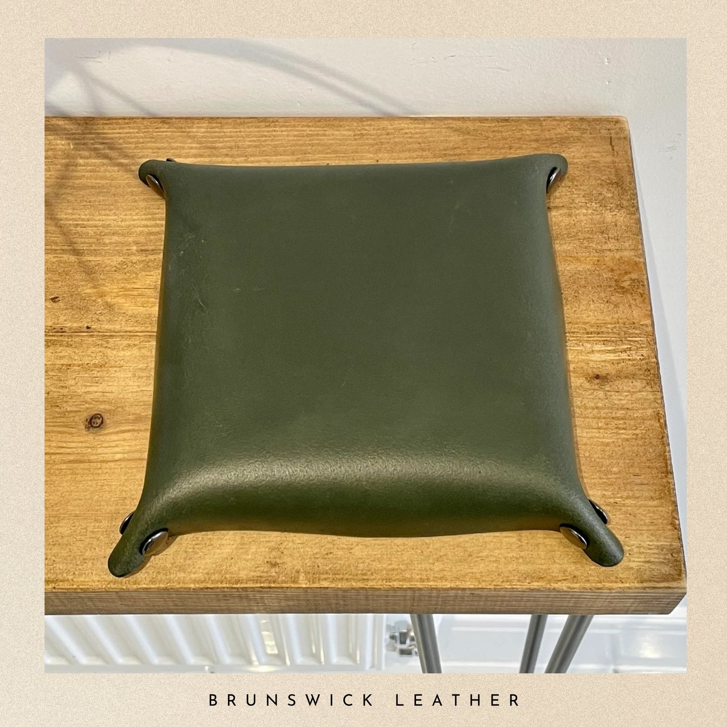 Green leather tray on a wooden surface with 'Brunswick Leather' branding.