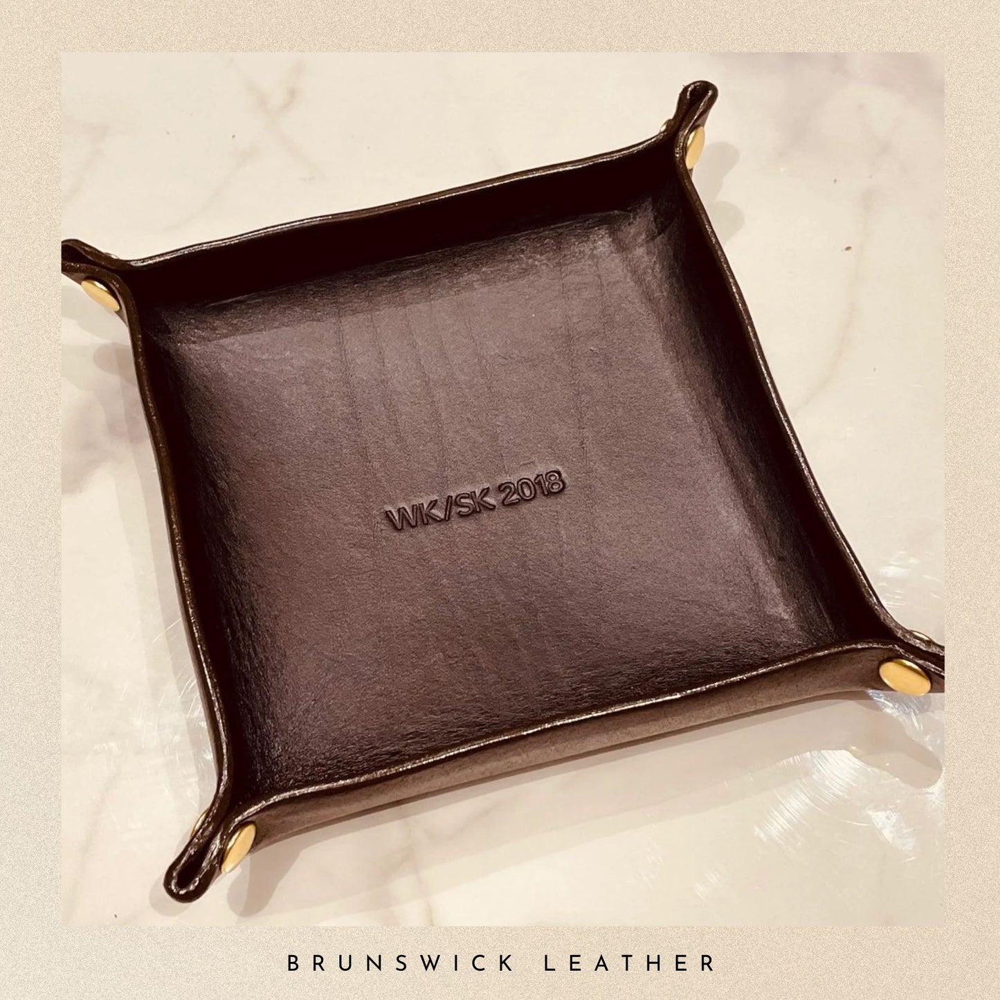 Brown leather tray with 'WJJSK 2018' embossed on it, on a beige background.