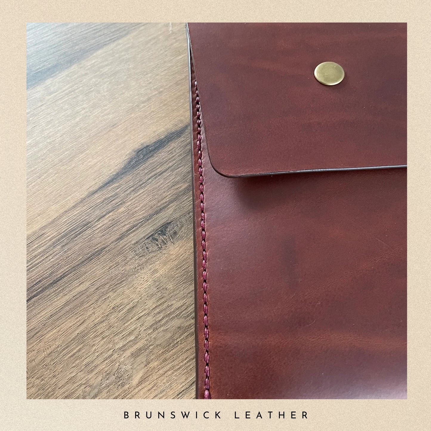 Brown leather pouch with gold button on a wooden surface, branded 'Brunswick Leather'.