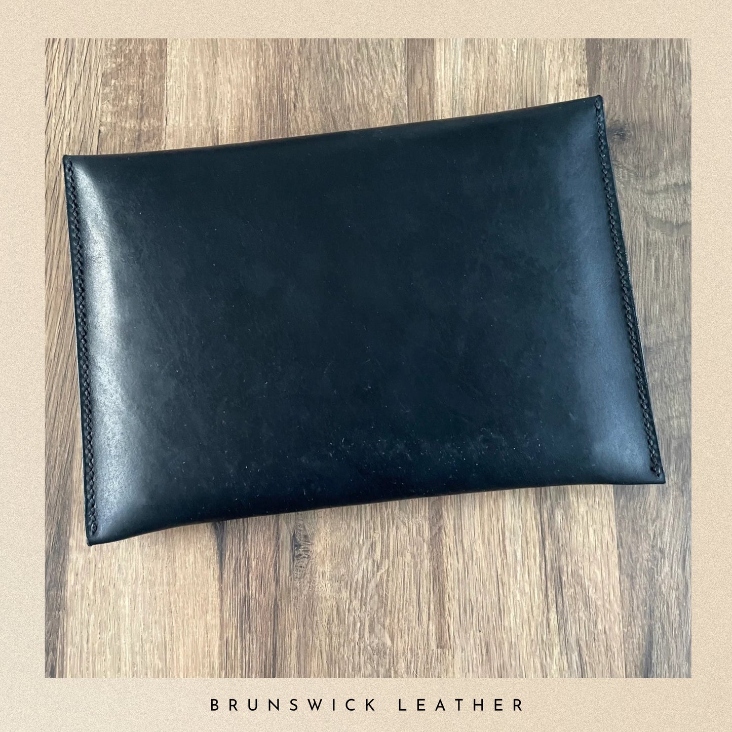 Black leather pouch on a wooden surface with 'Brunswick Leather' branding.