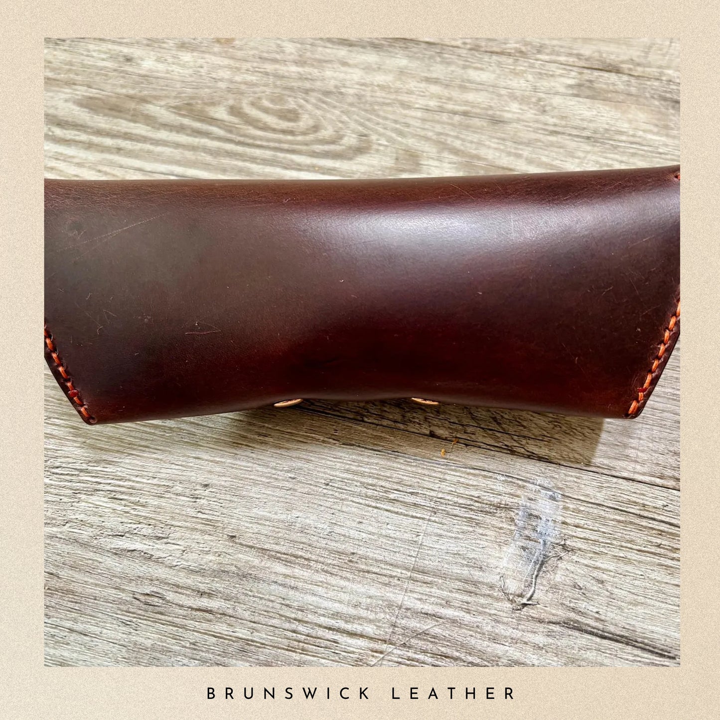 Brown leather sleeve on a wooden surface with 'Brunswick Leather' branding.