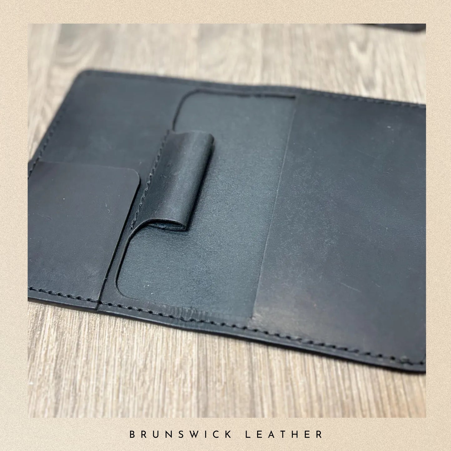 Black leather wallet on a wooden surface with 'Brunswick Leather' branding.