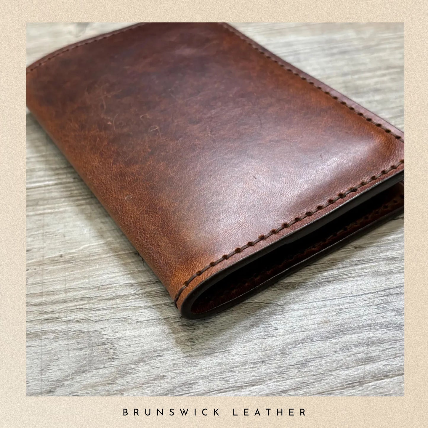 Brown leather wallet on a wooden surface with 'Brunswick Leather' branding.
