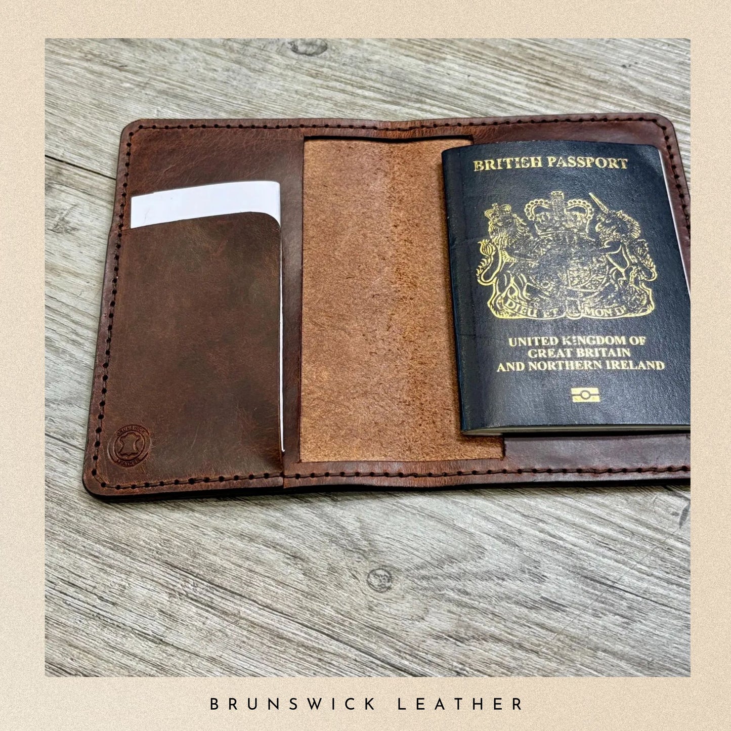 Brown leather passport holder with a British passport on a wooden surface, branded 'Brunswick Leather'.