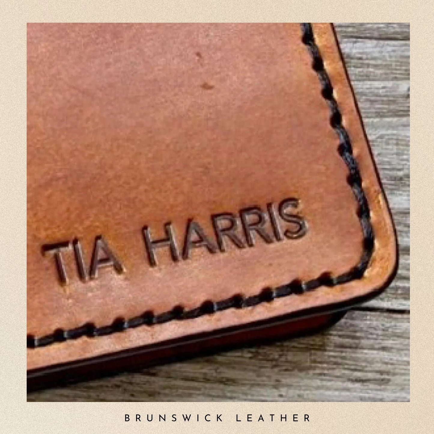 Brown leather wallet with 'TIA HARRIS' embossed on it, placed on a wooden surface.
