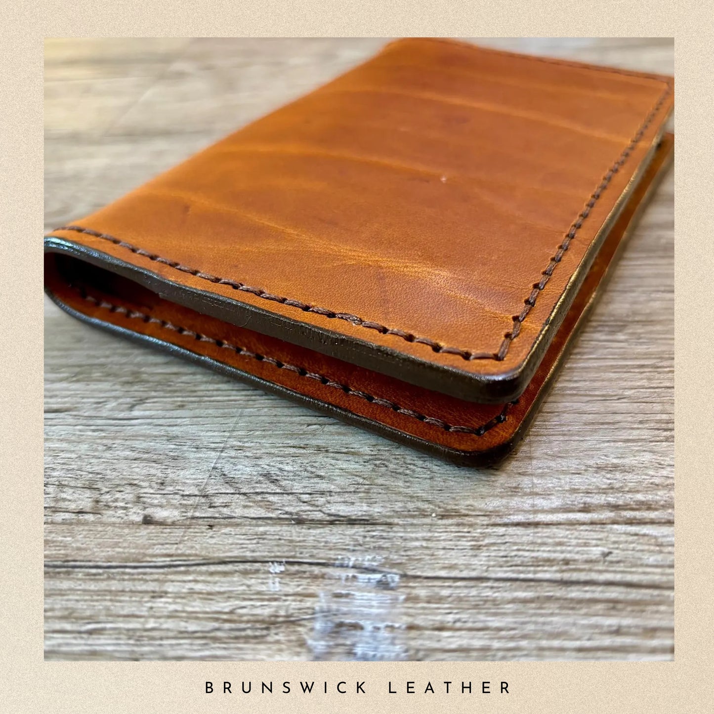 Brown leather wallet on a wooden surface with 'Brunswick Leather' branding.
