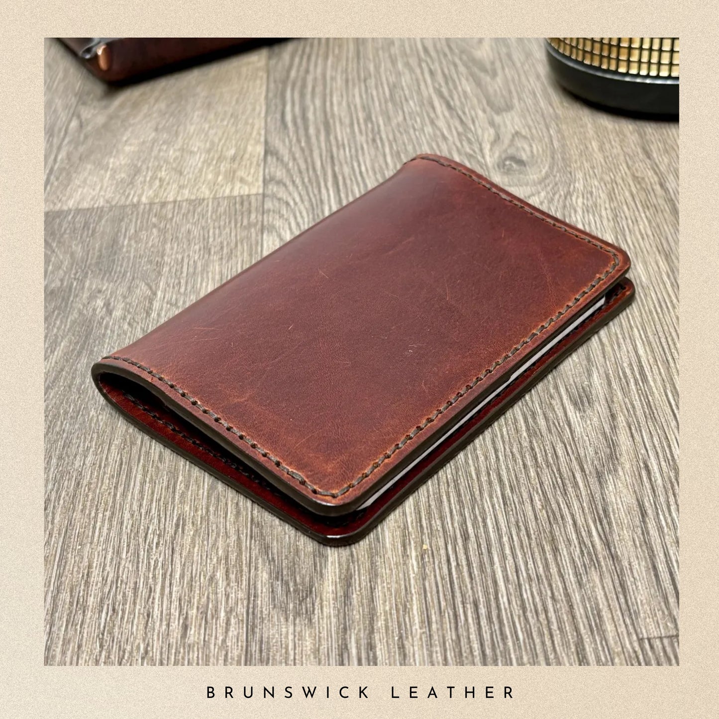 Brown leather wallet on a wooden surface with 'Brunswick Leather' branding.