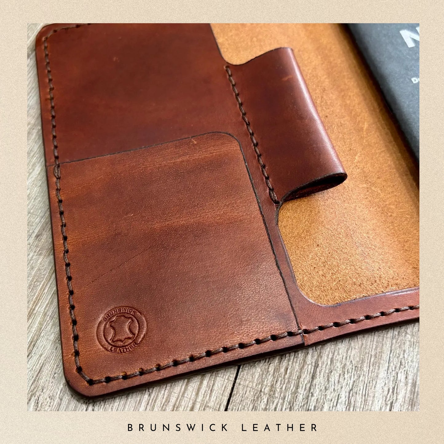 Brown leather wallet with visible stitching on a wooden surface, branded 'Brunswick Leather'.