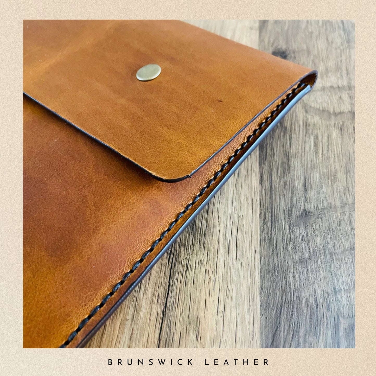 Brown leather wallet with visible stitching on a wooden surface, branded 'Brunswick Leather'.