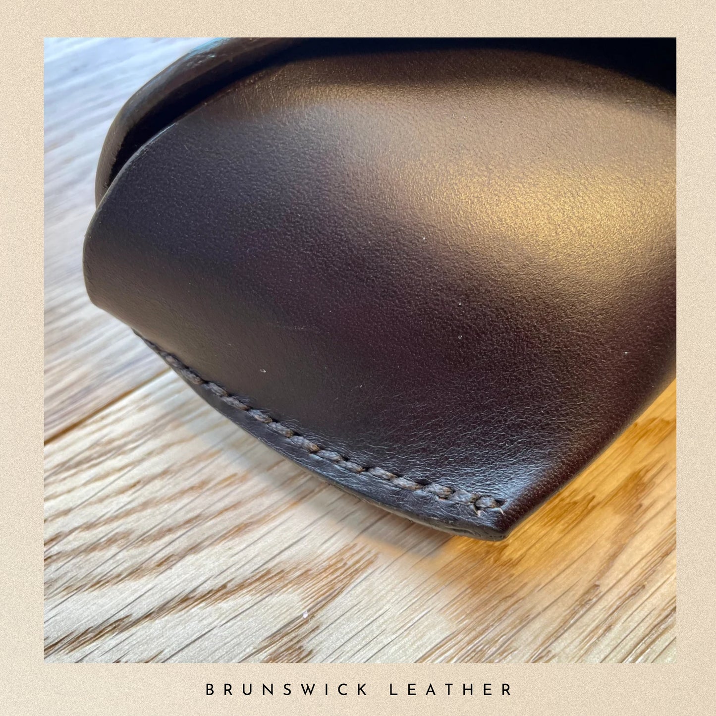 Close-up of a brown leather product on a wooden surface with 'Brunswick Leather' branding.