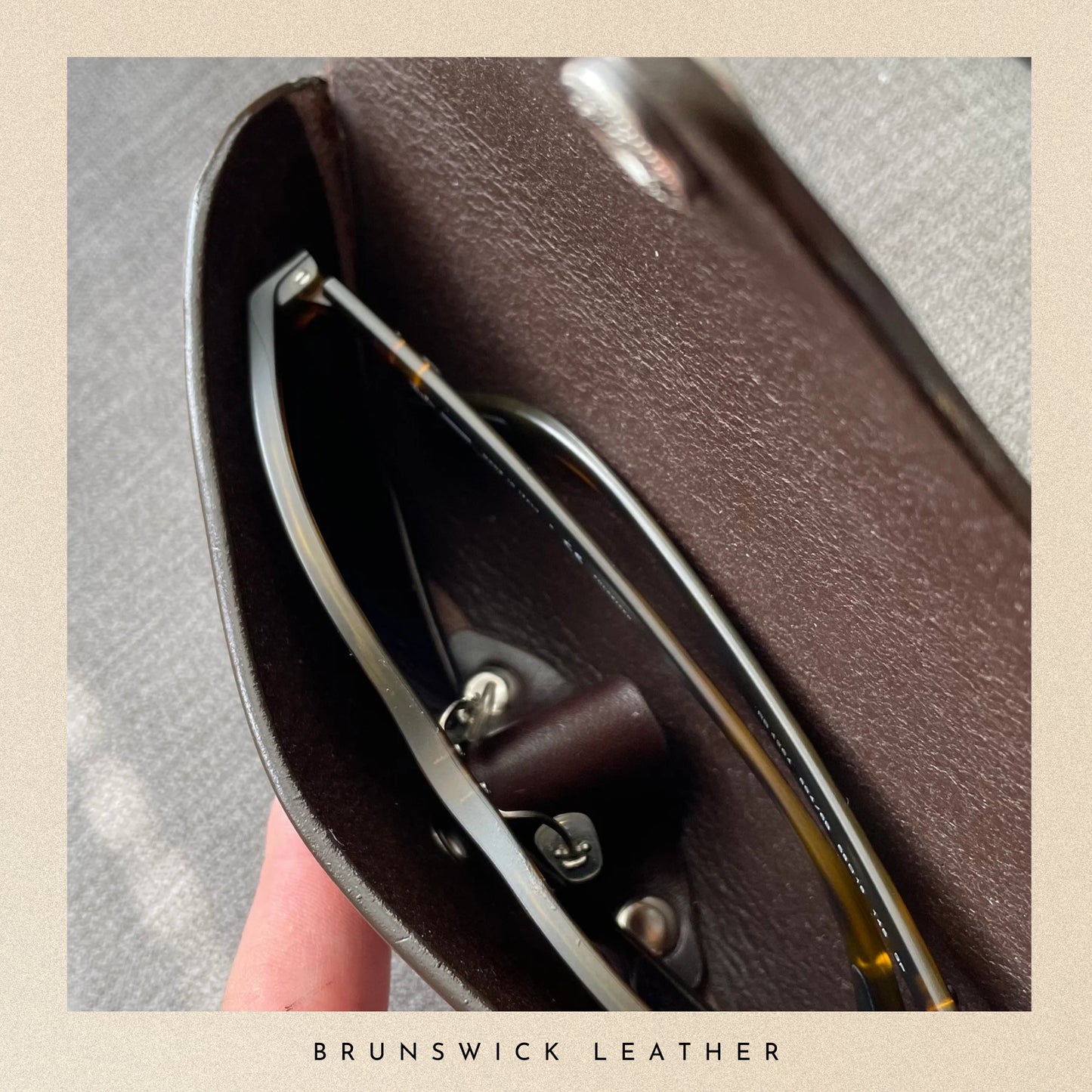 Brown leather sunglasses case with sunglasses inside, branded 'Brunswick Leather'.
