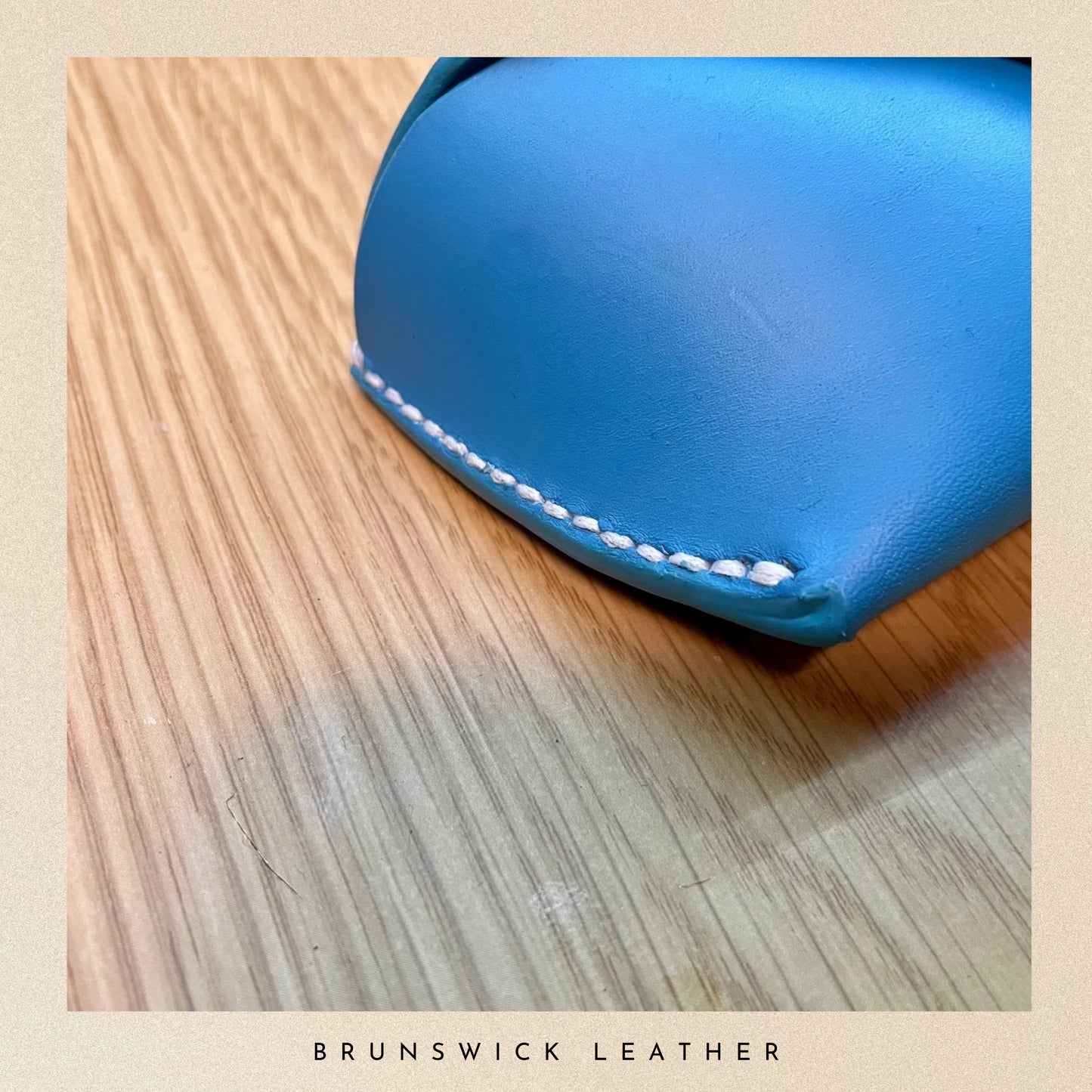 Blue leather wallet on a wooden surface with 'Brunswick Leather' branding.