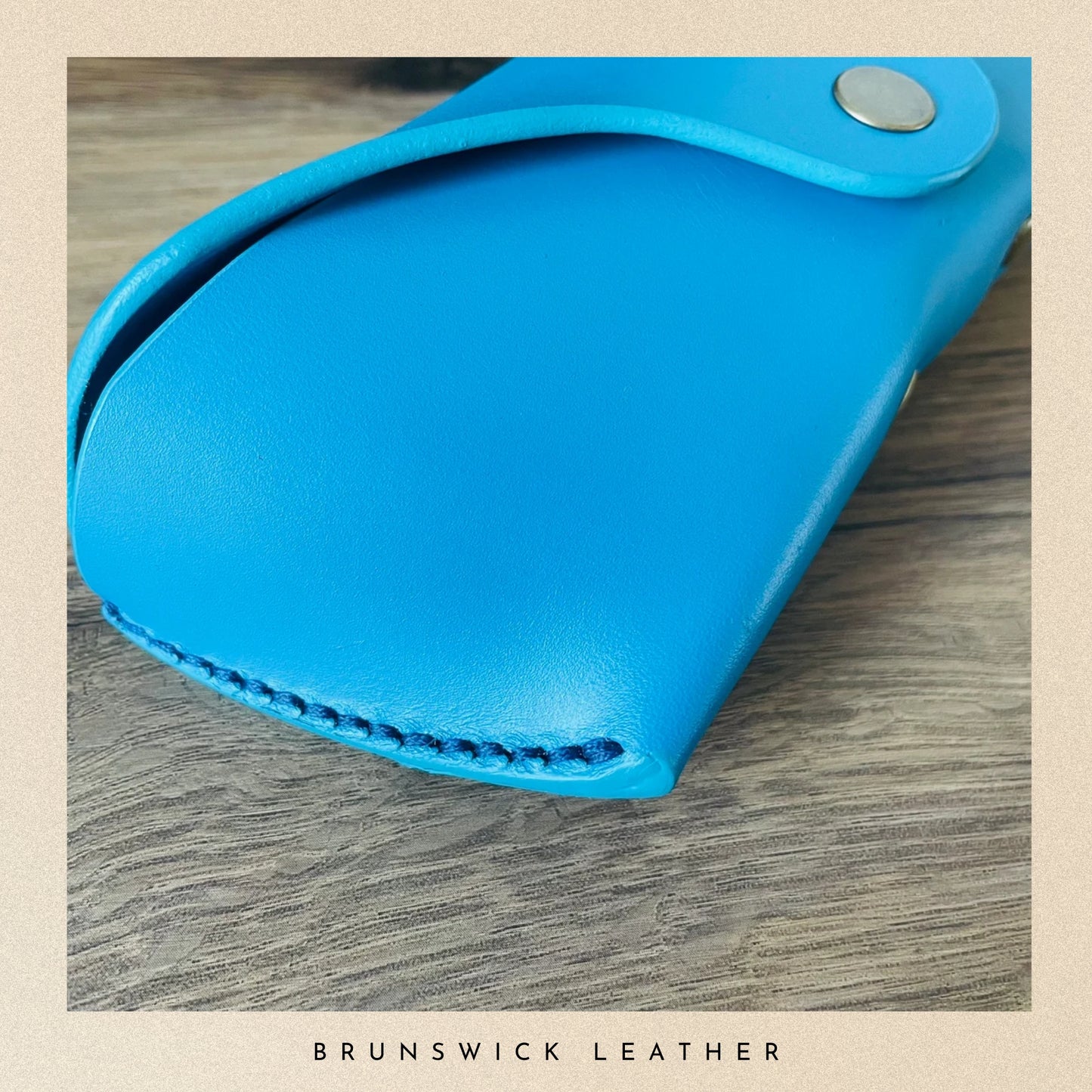 Blue leather case on a wooden surface with 'Brunswick Leather' branding.
