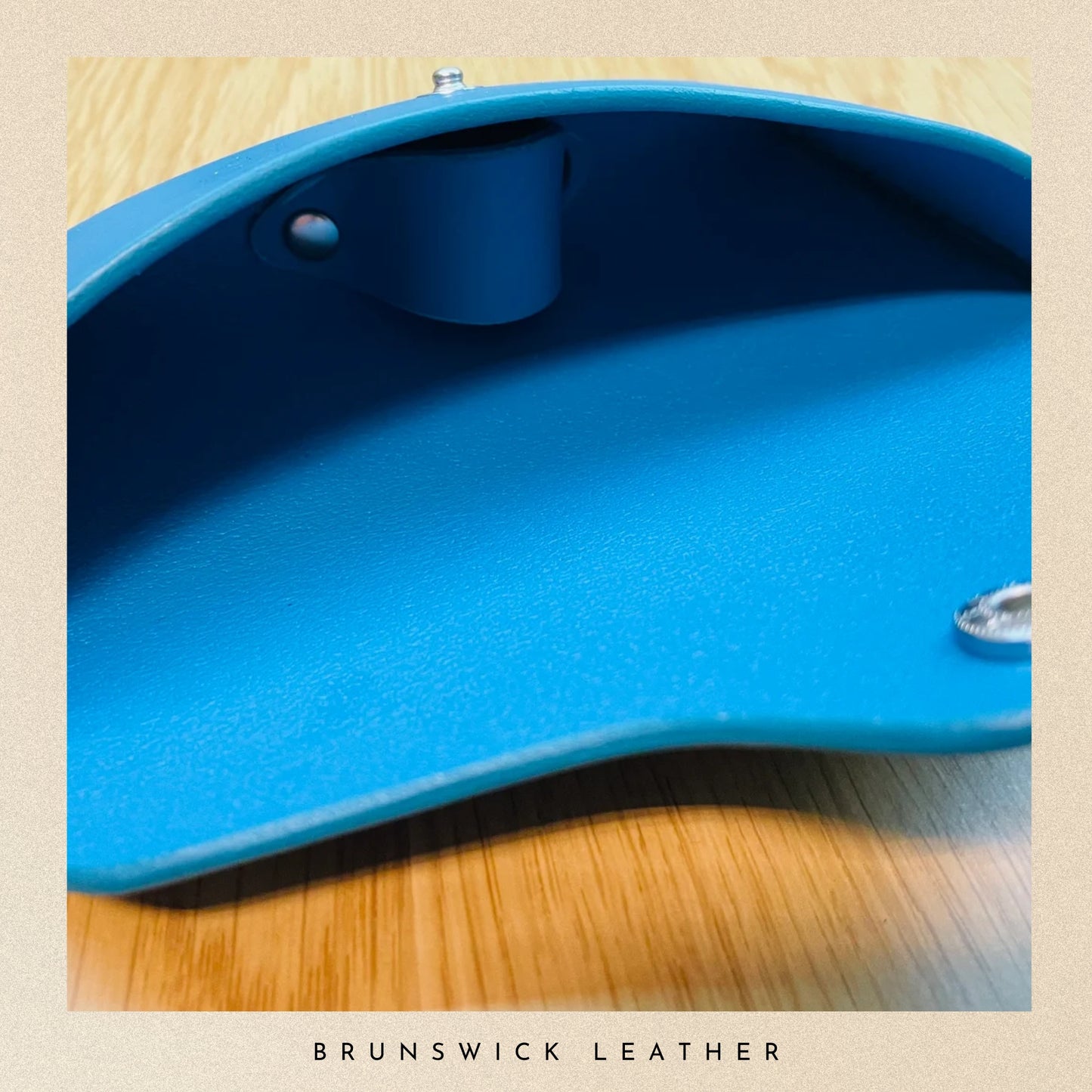 Close-up of a blue pool table felt on a wooden surface with 'Brunswick Leather' branding.