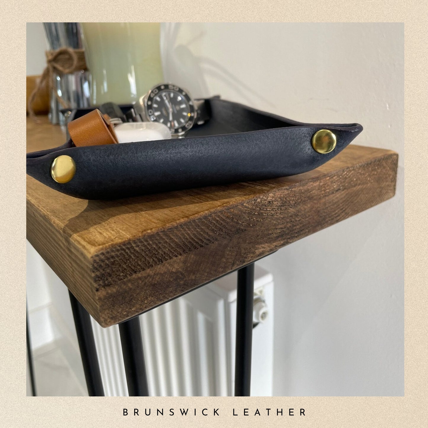 Black leather tray with gold accents on a wooden surface, branded 'Brunswick Leather'.