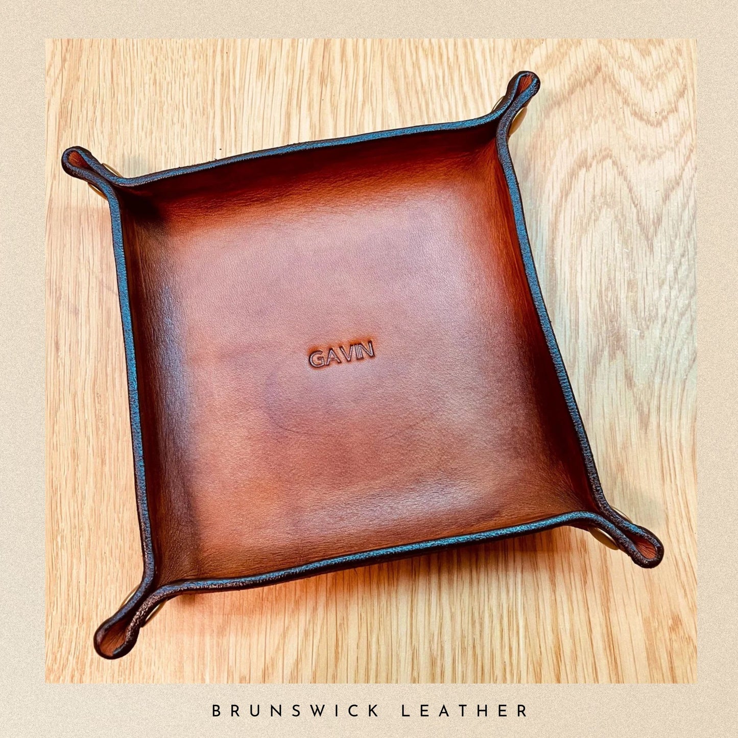 Brown leather tray with 'Gavin' engraving on a wooden surface, branded 'Brunswick Leather'.