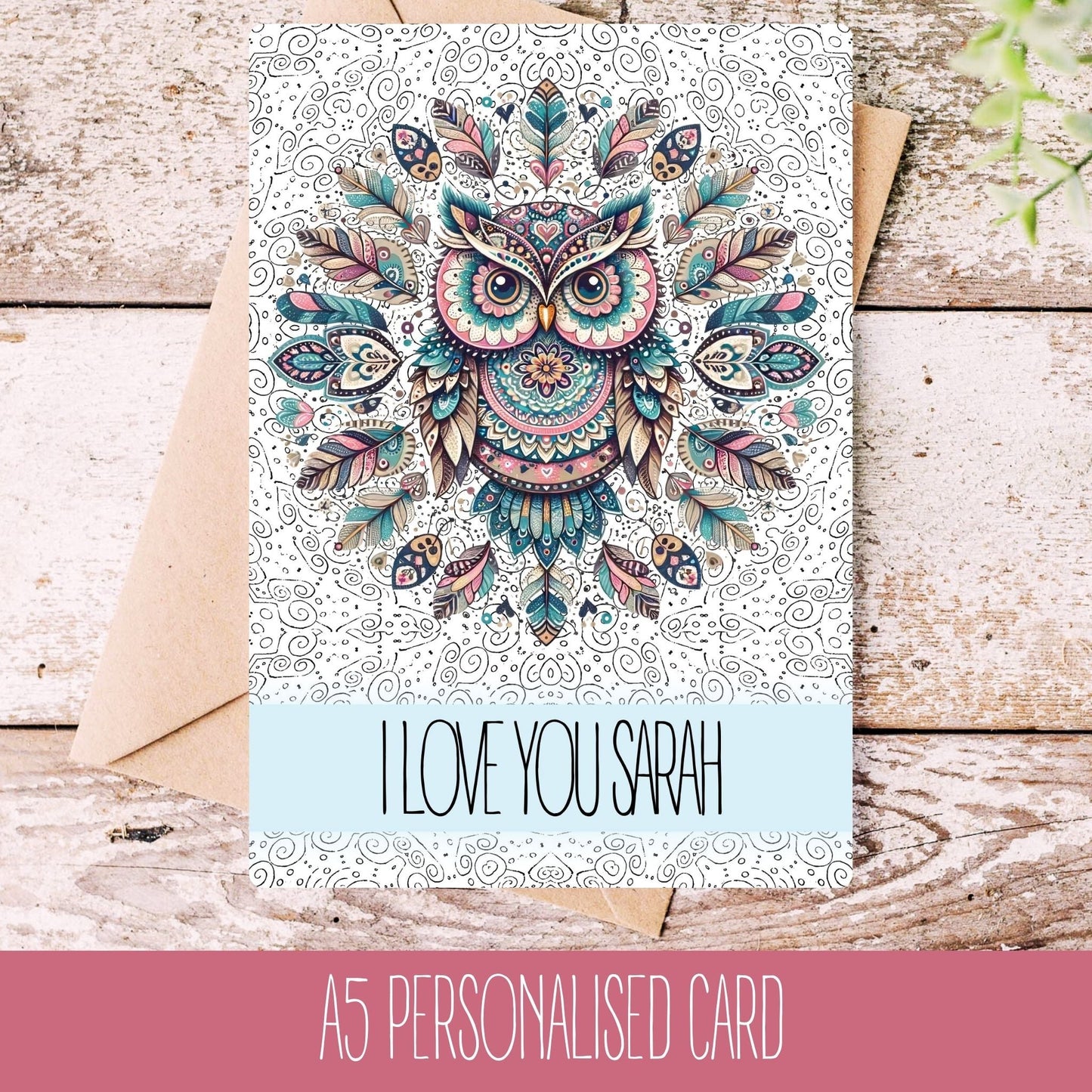A personalised mandala birthday card with a colourful owl design and a text personalization reading 'I love you Sarah'. The card is placed on a wooden surface with a white envelope beside it.