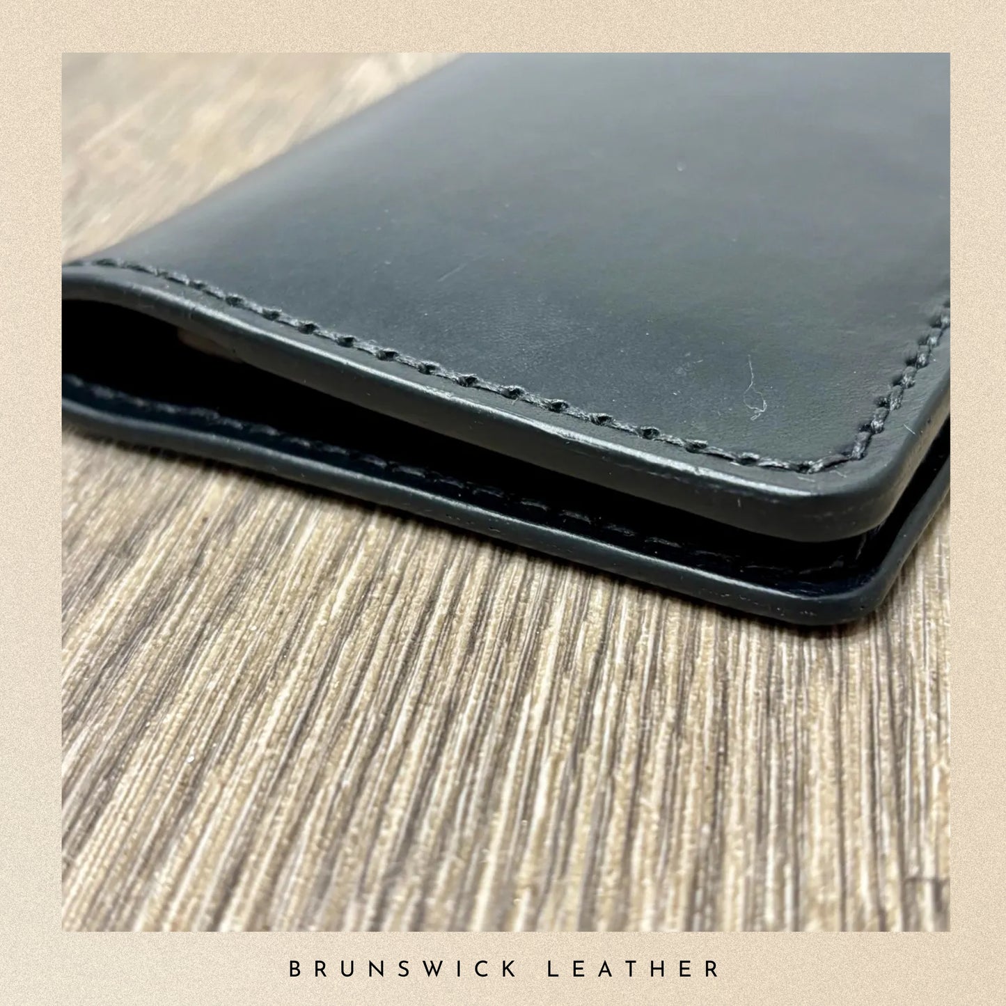 Black leather wallet on a wooden surface with 'Brunswick Leather' branding.