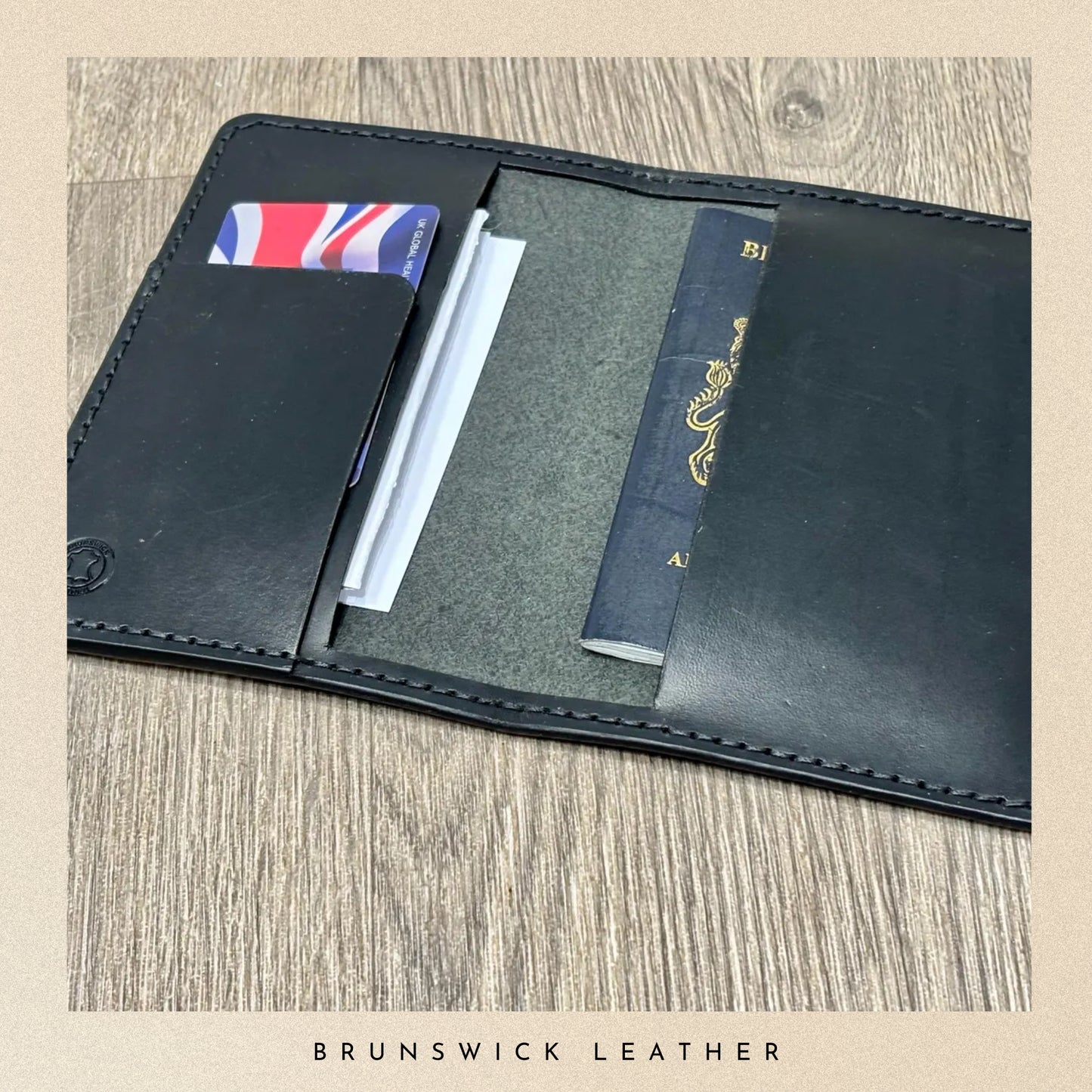 Black leather travel wallet with passport and card holder on a wooden surface, branded 'Brunswick Leather'.