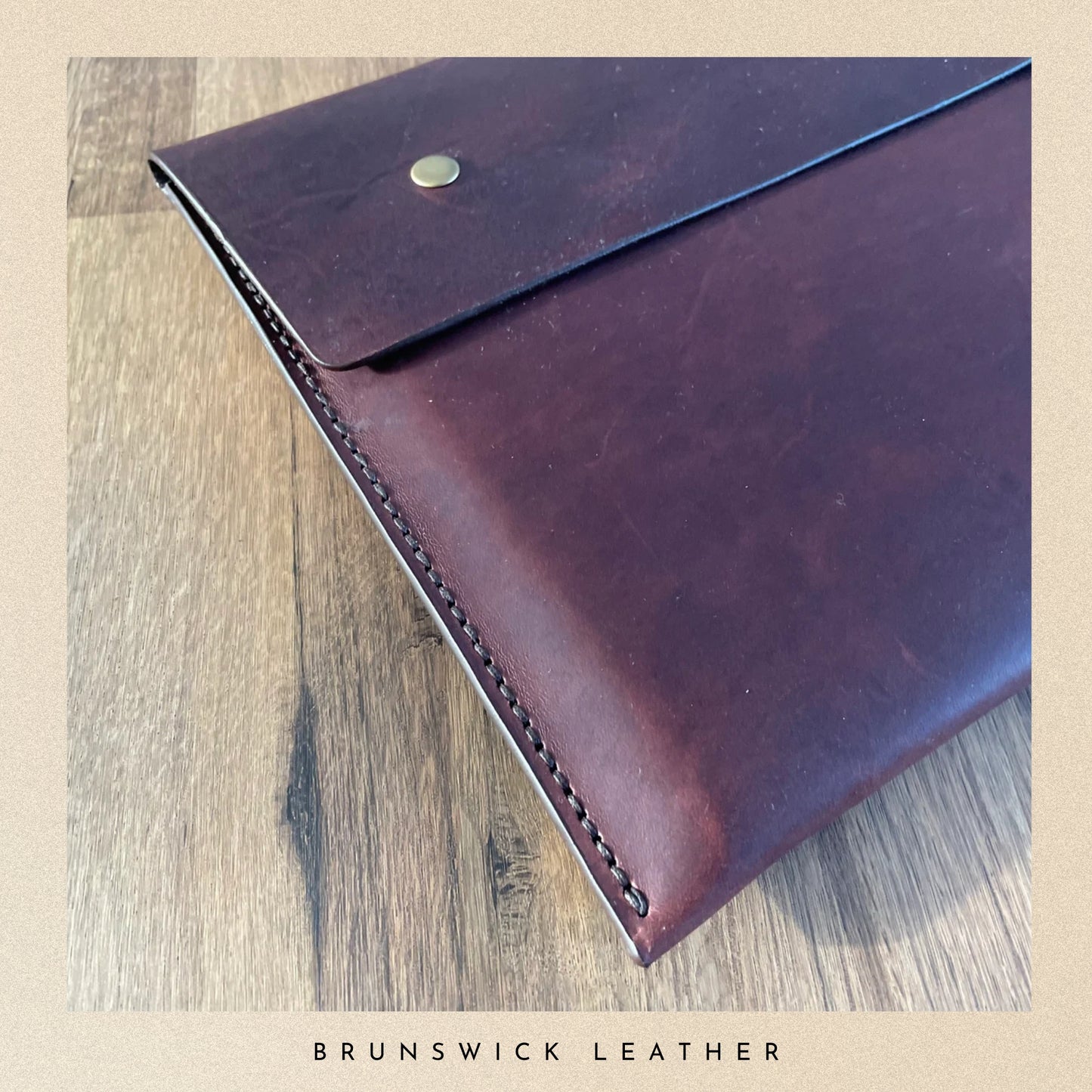 Brown leather envelope on a wooden surface with 'Brunswick Leather' branding.