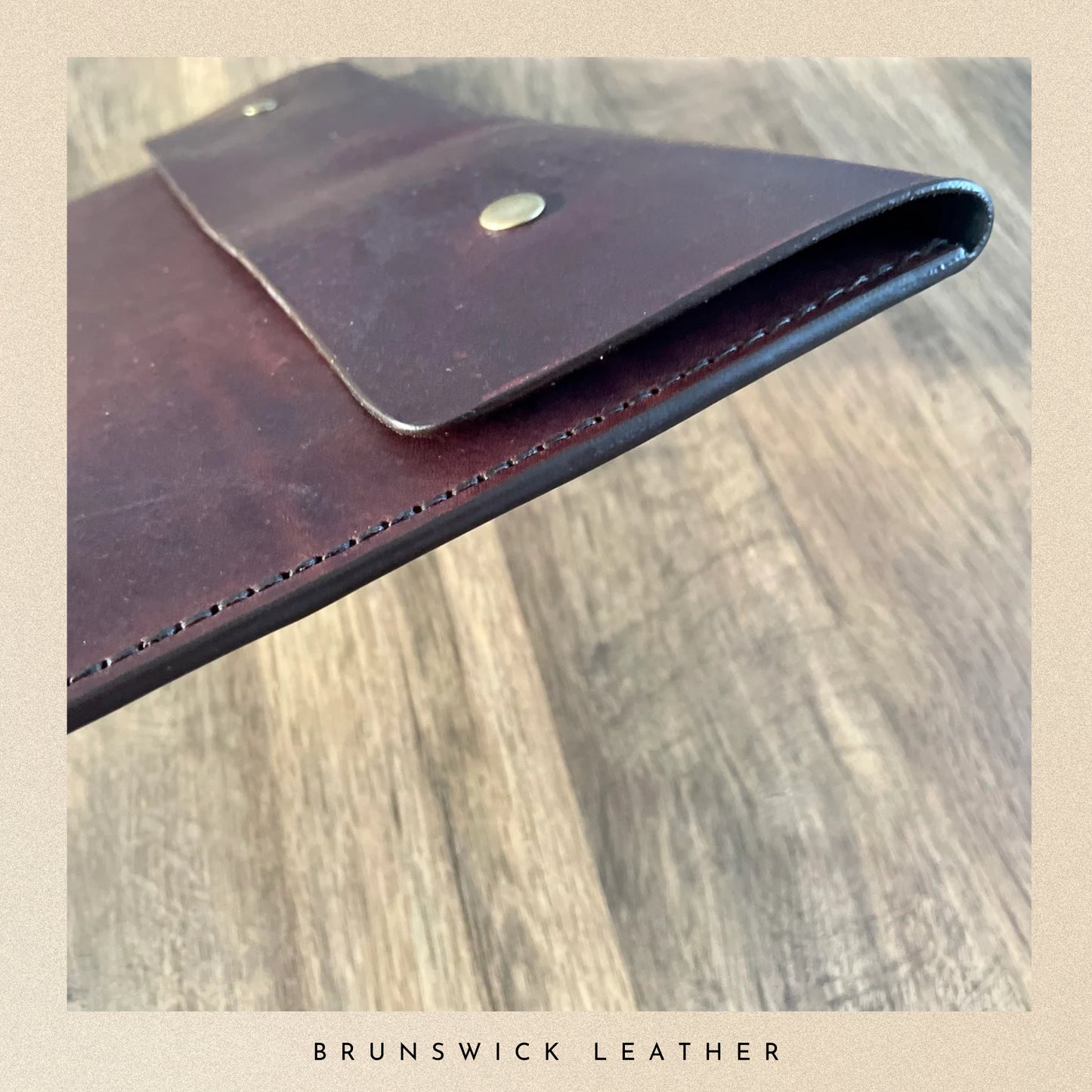 Brown leather wallet with visible stitching on a wooden surface, branded 'Brunswick Leather'.