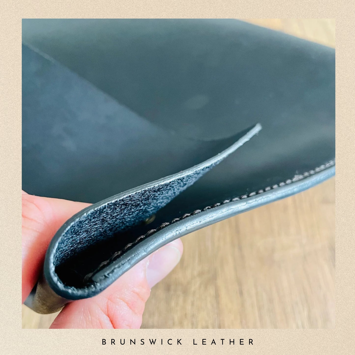 Close-up of a hand holding a piece of dark blue leather with 'Brunswick Leather' branding.