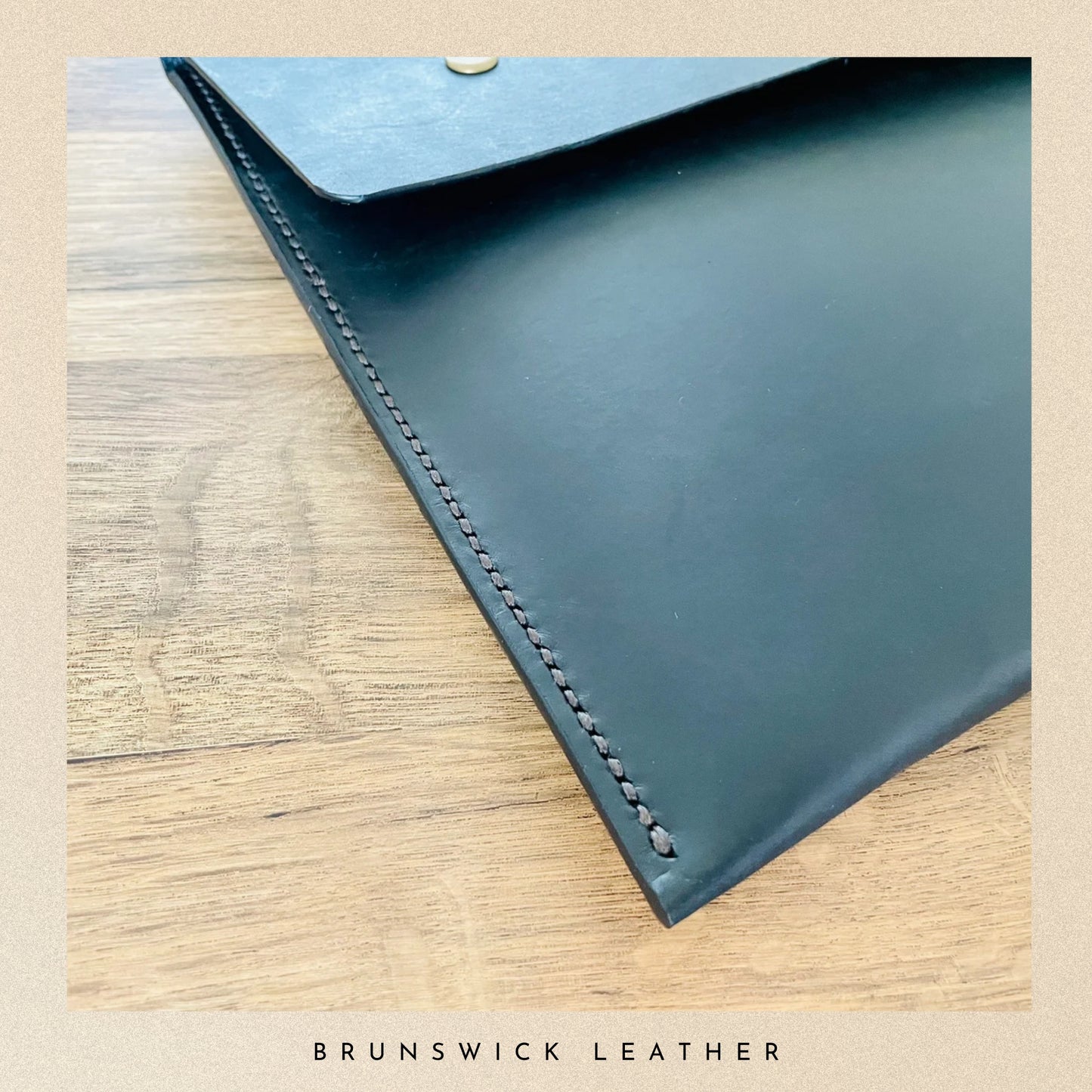 Blue leather envelope on a wooden surface with 'Brunswick Leather' branding.