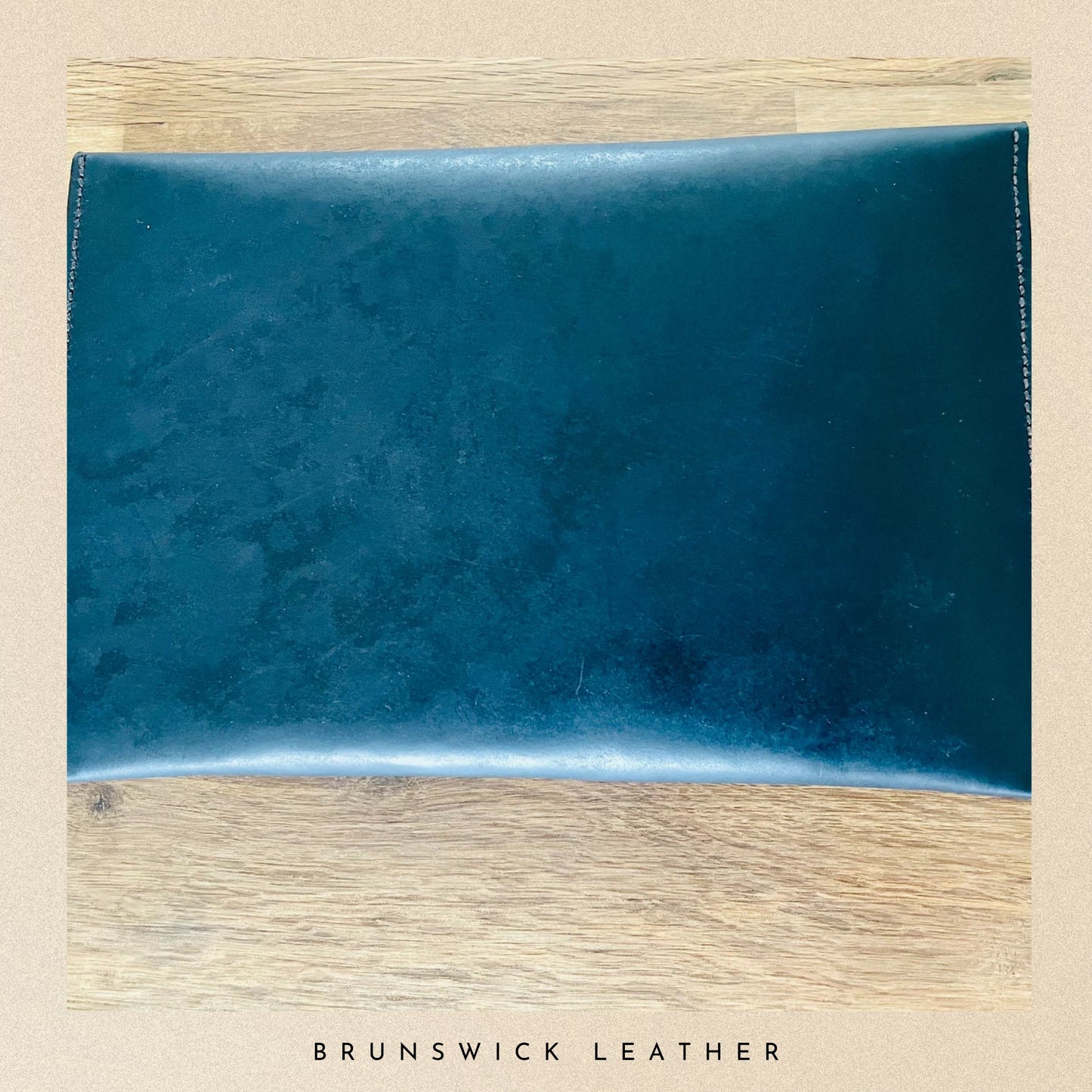 Blue leather sample on a wooden surface with 'Brunswick Leather' branding.