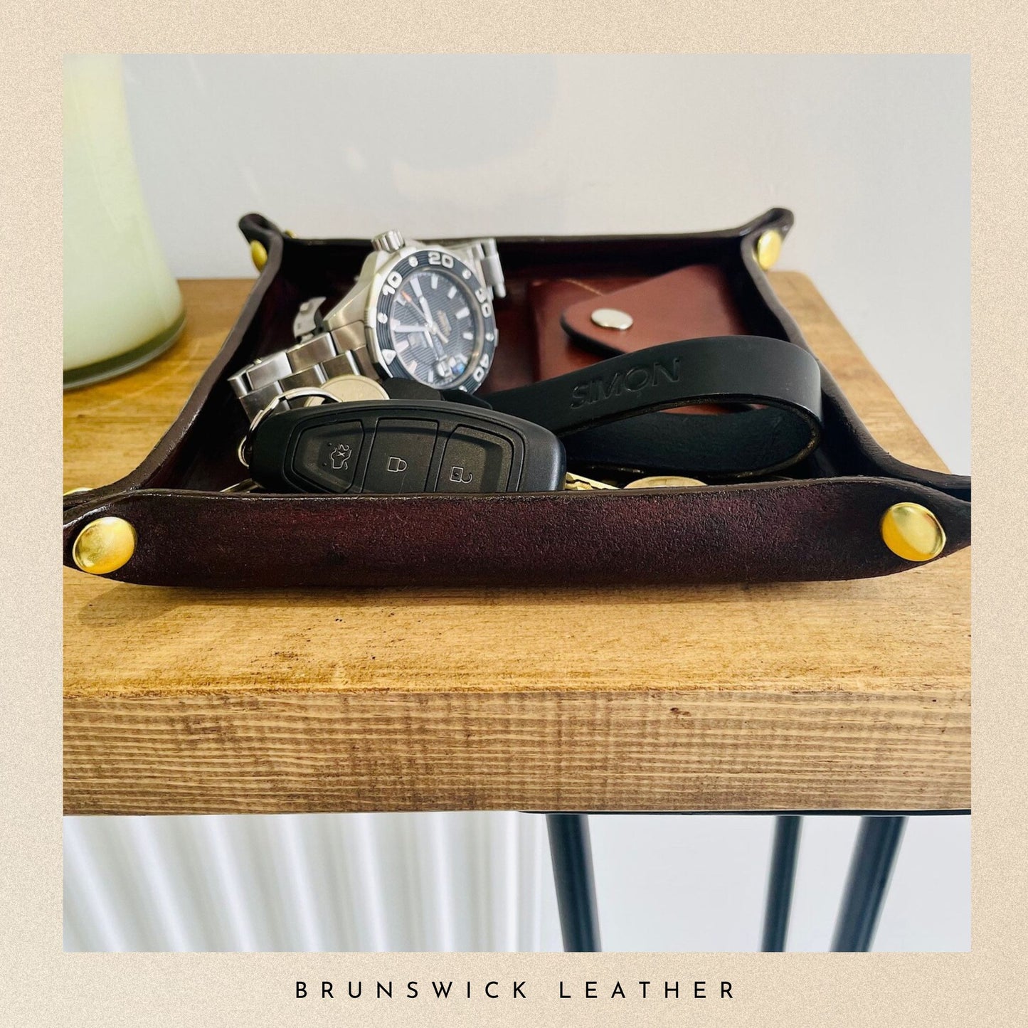 Leather tray with watch, keys, and wallet on a wooden surface with 'Brunswick Leather' branding.