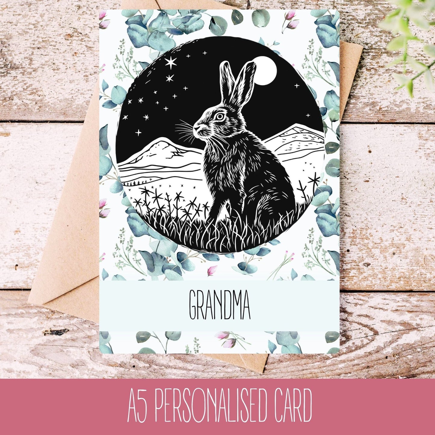 A personalised greeting card with a graphic of a hare (rabbit) on it, set against a floral and moonlit background, with the word 'GRANDMA' printed at the bottom.