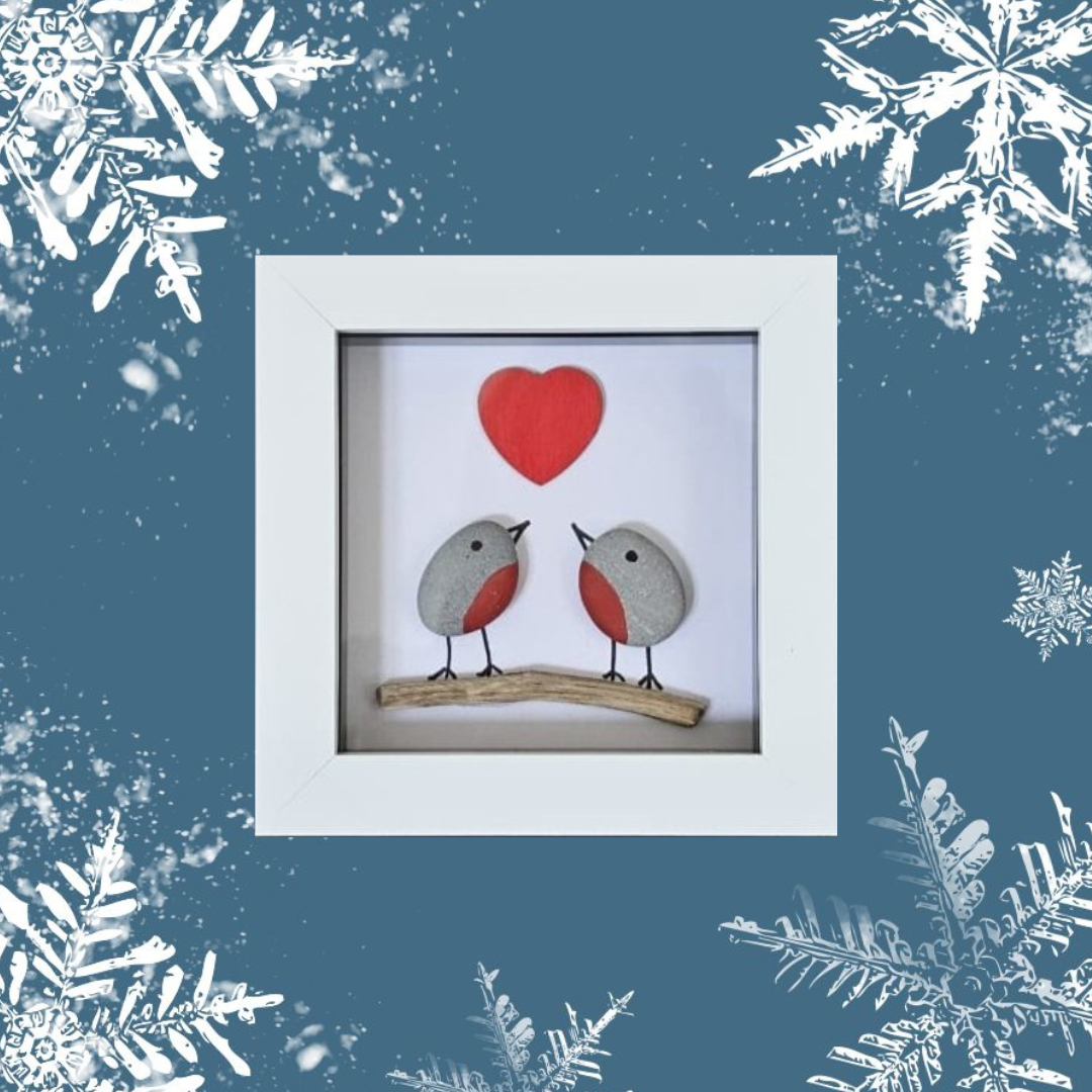 Framed artwork of two robins on a branch with a red heart above, surrounded by snowflakes on a blue background.